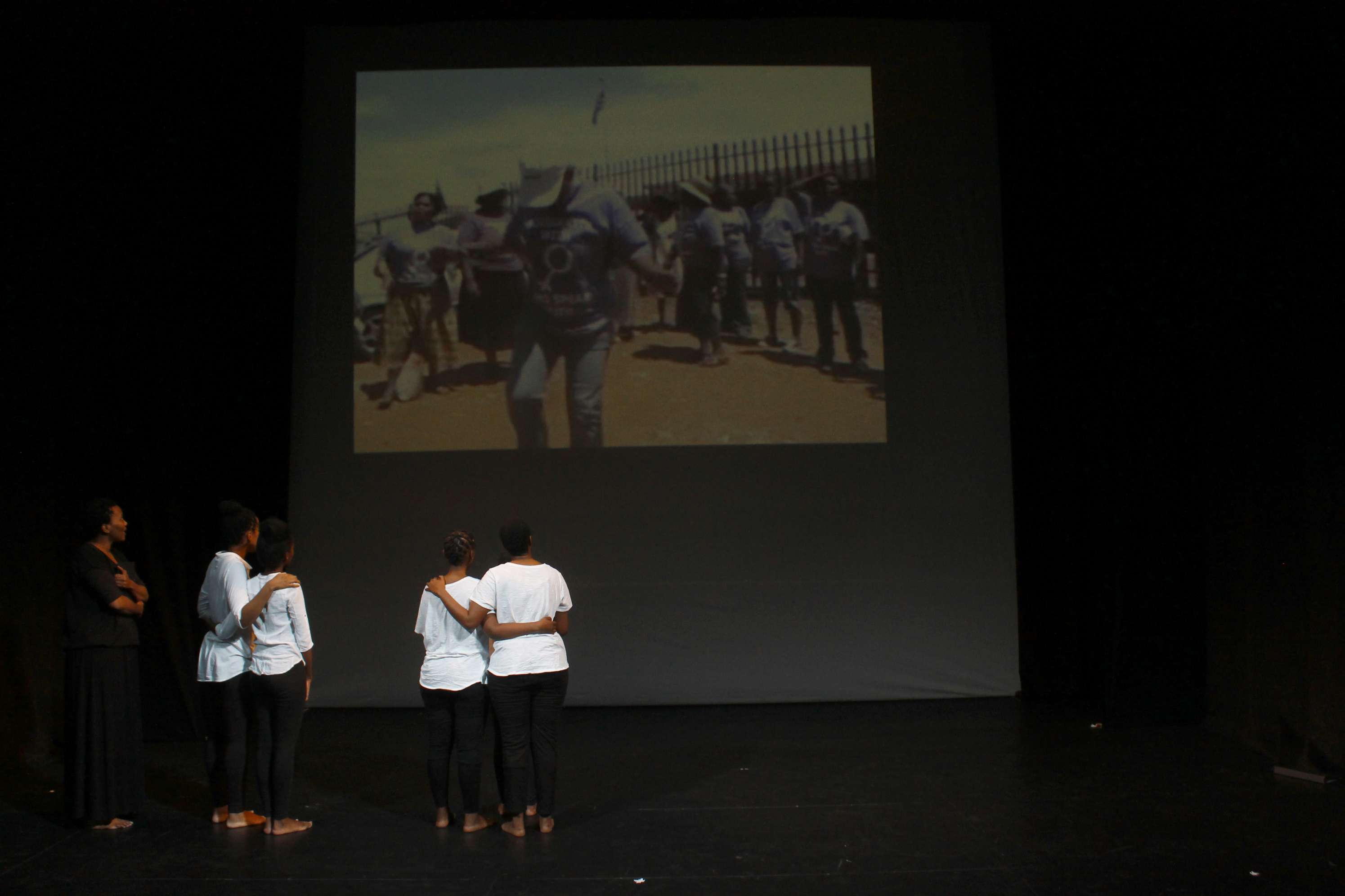 The performers watch research footage. <br>Photo Credit: (c) Madoda Mkhobeni